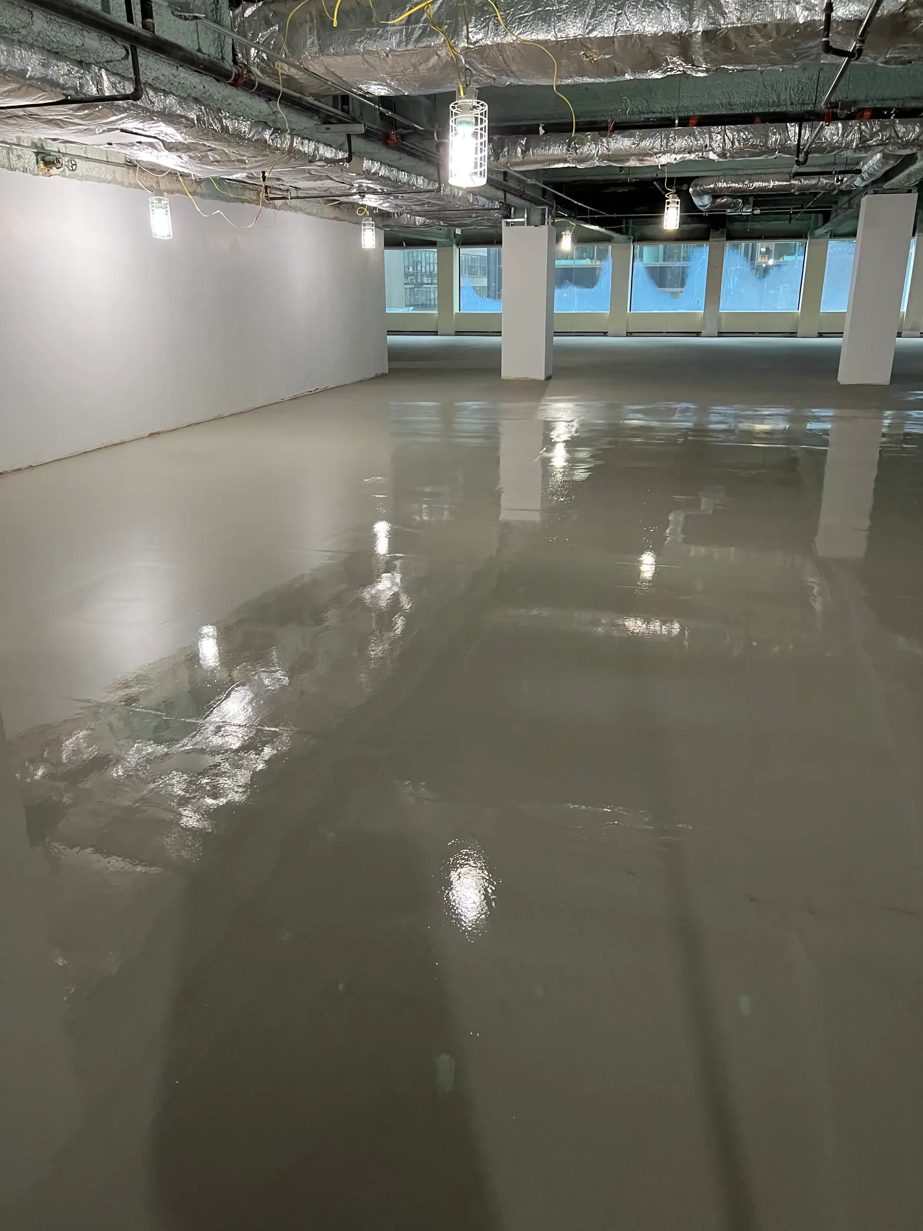 Glossy self-leveling underlayment poured across a high-rise office floor by Core Floorings Inc
