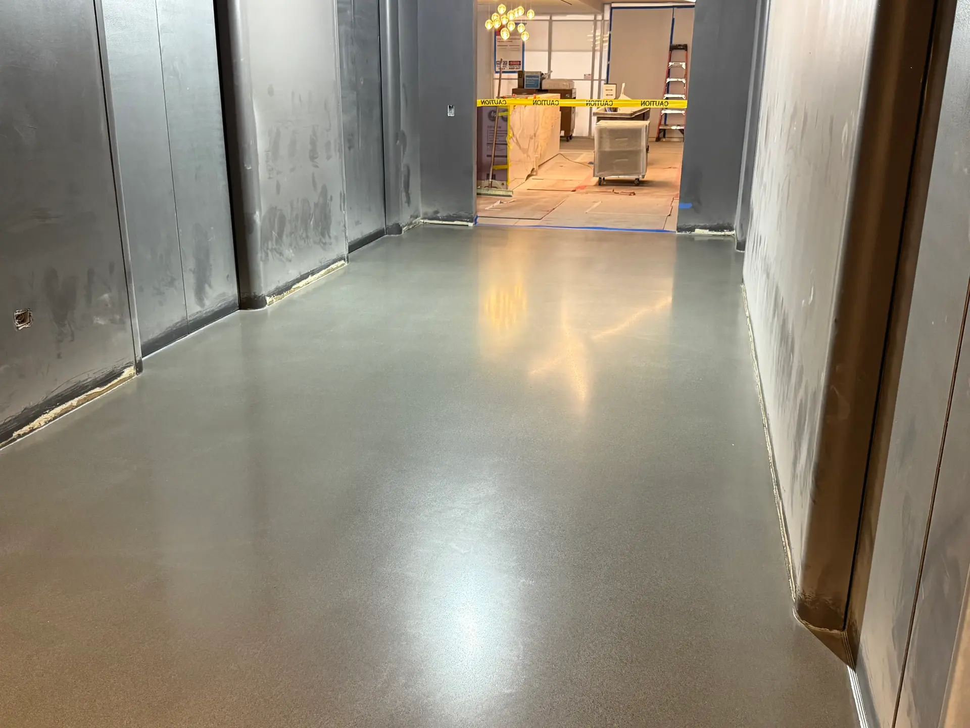 Gray polishable concrete topping in a construction-stage corridor by Core Floorings Inc