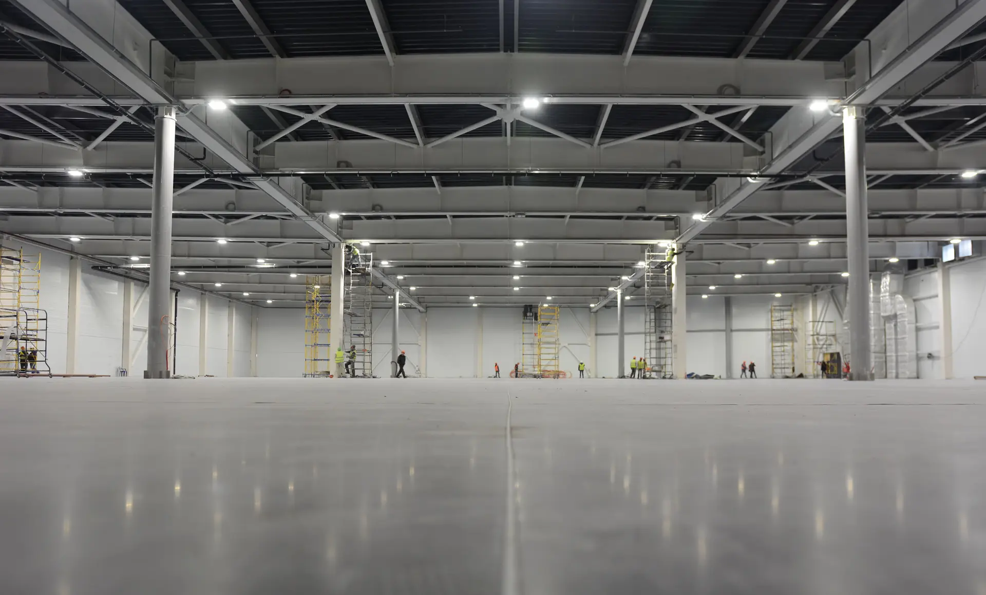 Large polished concrete warehouse floor with saw-cut joint under steel framing, finished by Core Floorings Inc