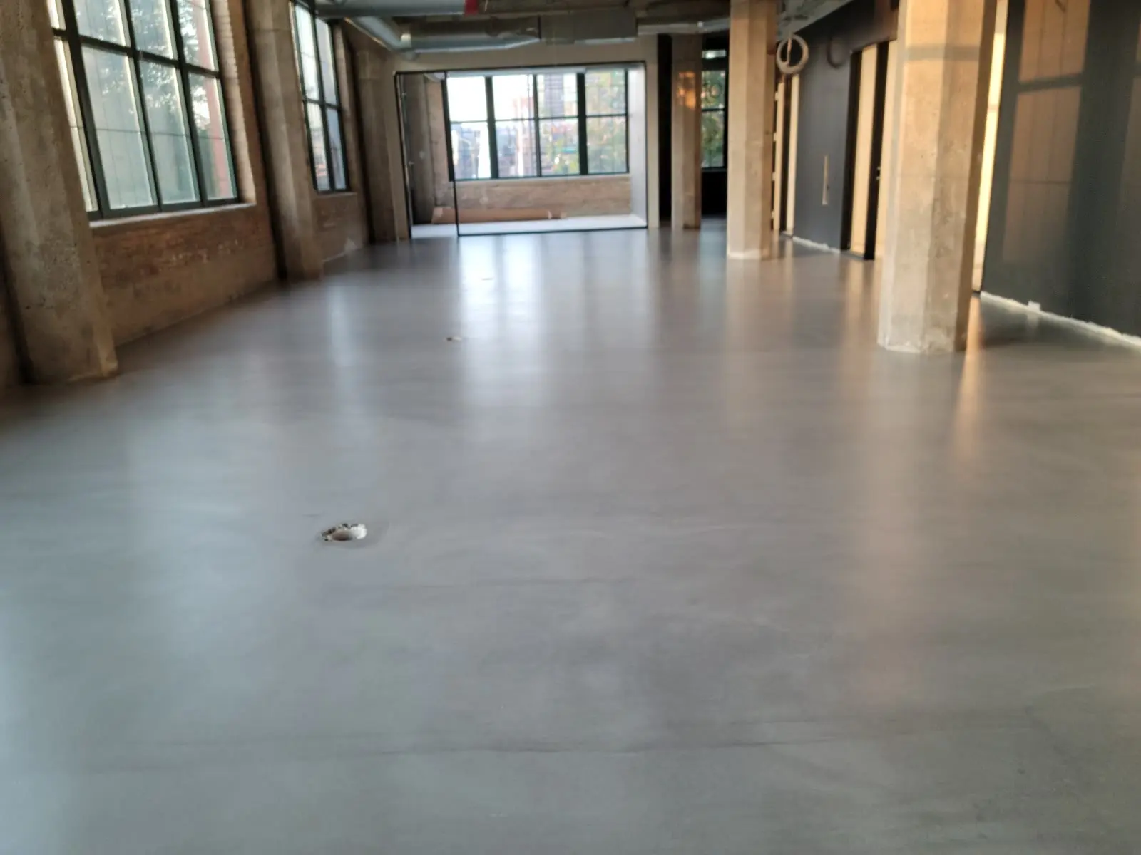 Sealed poured concrete topping in a brick and timber loft space by Core Floorings Inc