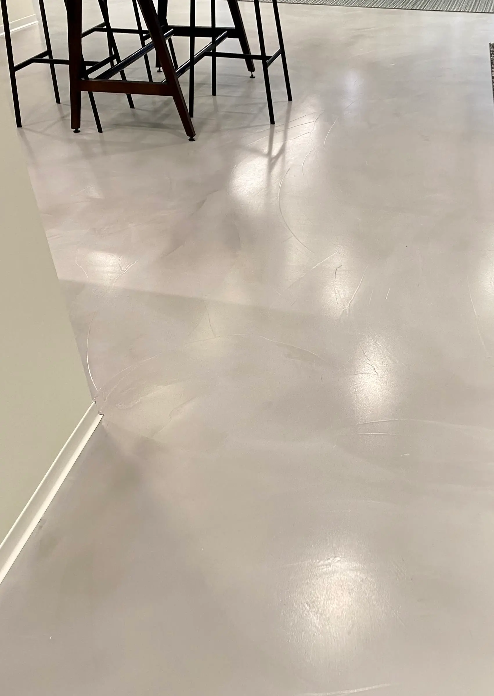 Troweled skim coat finish on a commercial lounge floor beside bar stools by Core Floorings Inc