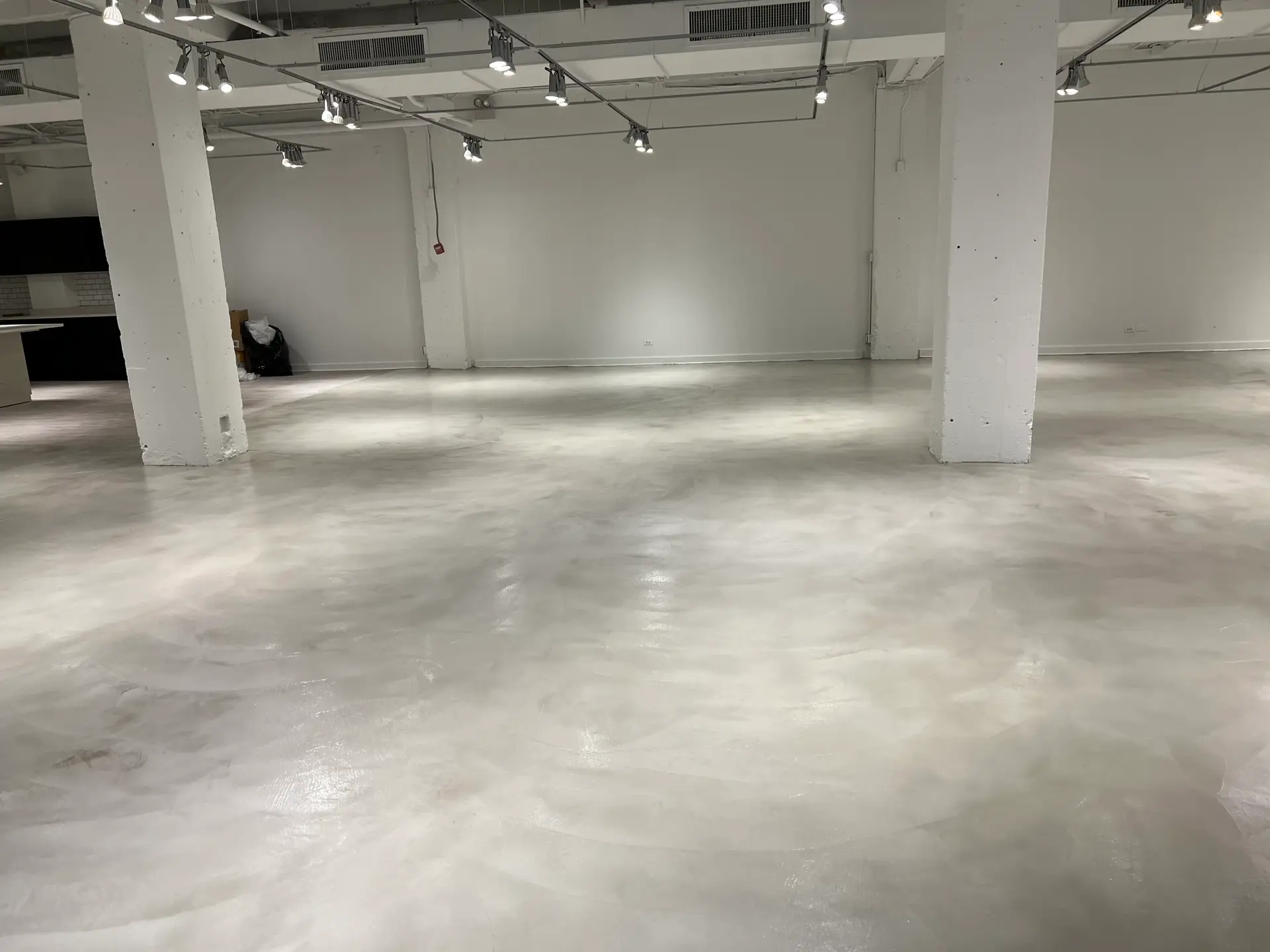 Light gray troweled topping with a soft marbled finish in a white showroom space by Core Floorings Inc